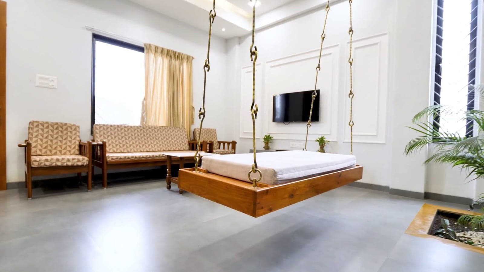 Living room with a wooden jhula and indoor plant court, Shinde House, Charholi, Pune